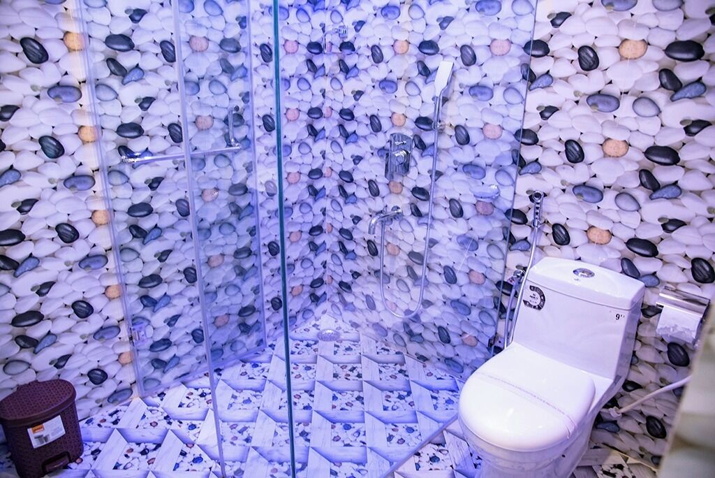 A bathroom with a unique pebble wall design and a modern toilet.