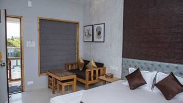 Een slaapkamer met een bed, een houten tafel, een bank en een groot raam.