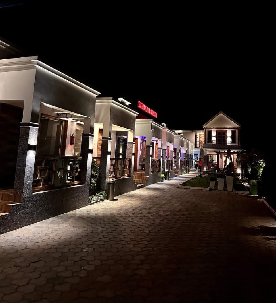 A nighttime view of a hotel corridor with illuminated storefronts and a paved walkway.