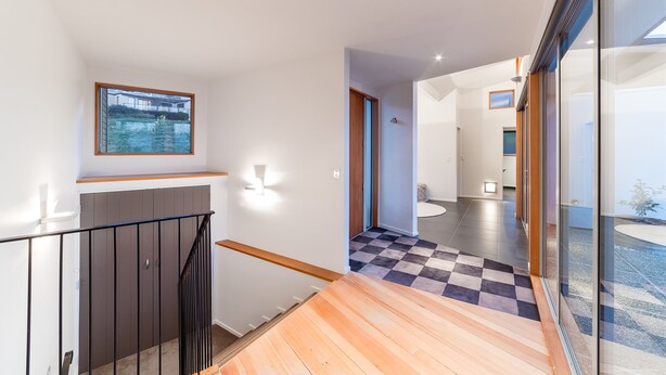 A modern interior with a staircase, a checkered floor, and a view through glass doors. - WHAKATA ON WHITBOURN (Queenstown)