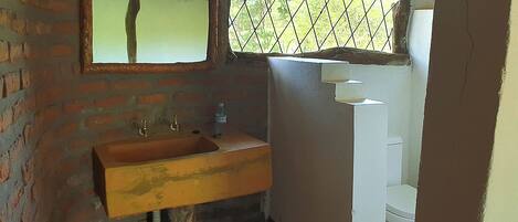 Un baño con lavamanos de madera, un espejo y un inodoro blanco.