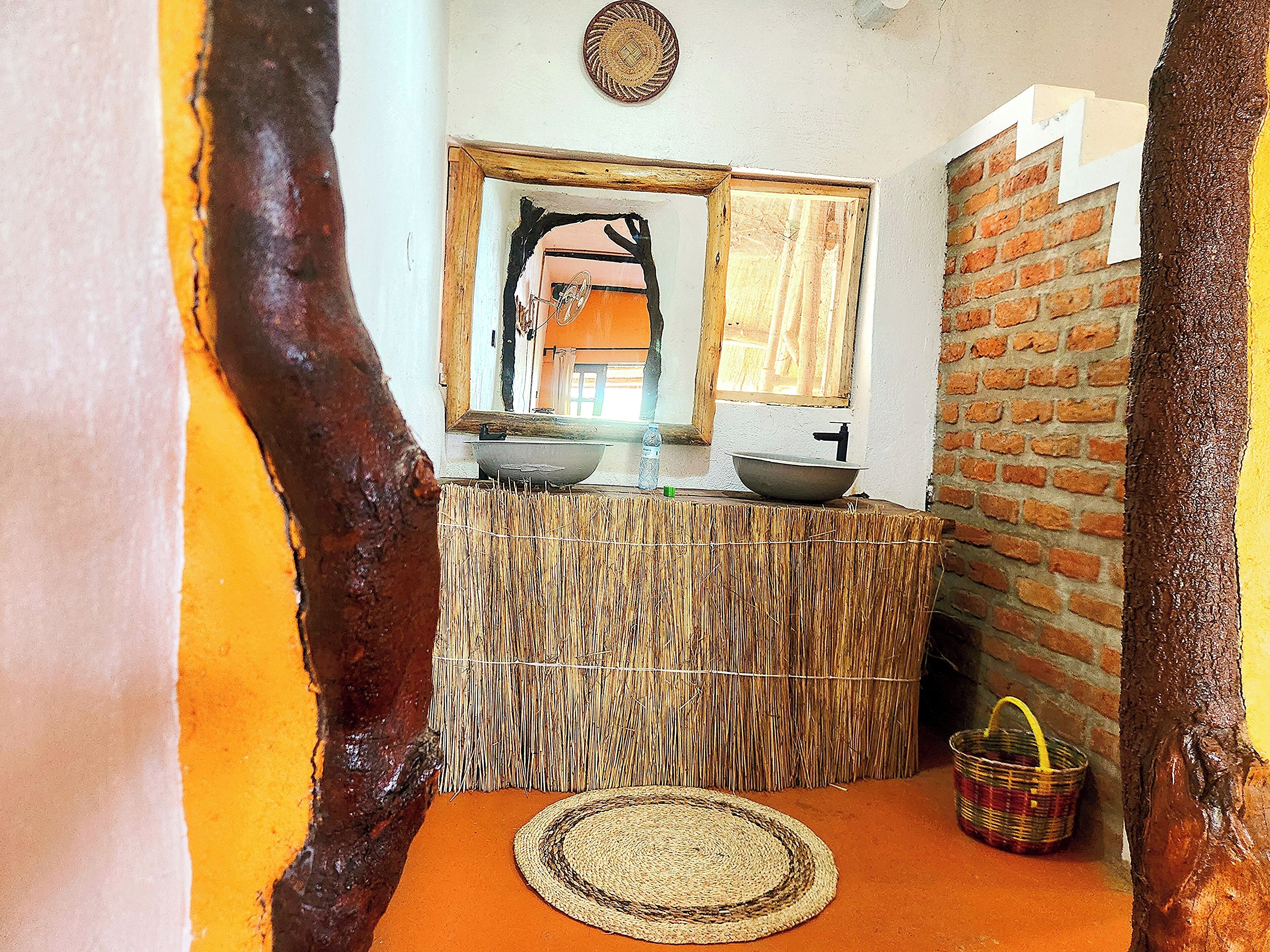A rustic bathroom with a woven counter, a round mat, and a hanging basket.