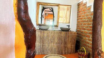 A rustic bathroom with a woven counter, a round mat, and a hanging basket.