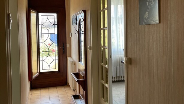 A hallway with a tiled floor, a radiator, a door with a glass panel, and a wall-mounted picture. - Séjour en Pavillon Proche des Transports et des Évènements (Aulnay-sous-Bois)