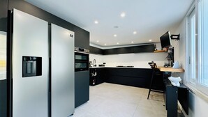 A modern kitchen with a built-in refrigerator, oven, and water dispenser. - YourHome - AC Luxury House (Meta)