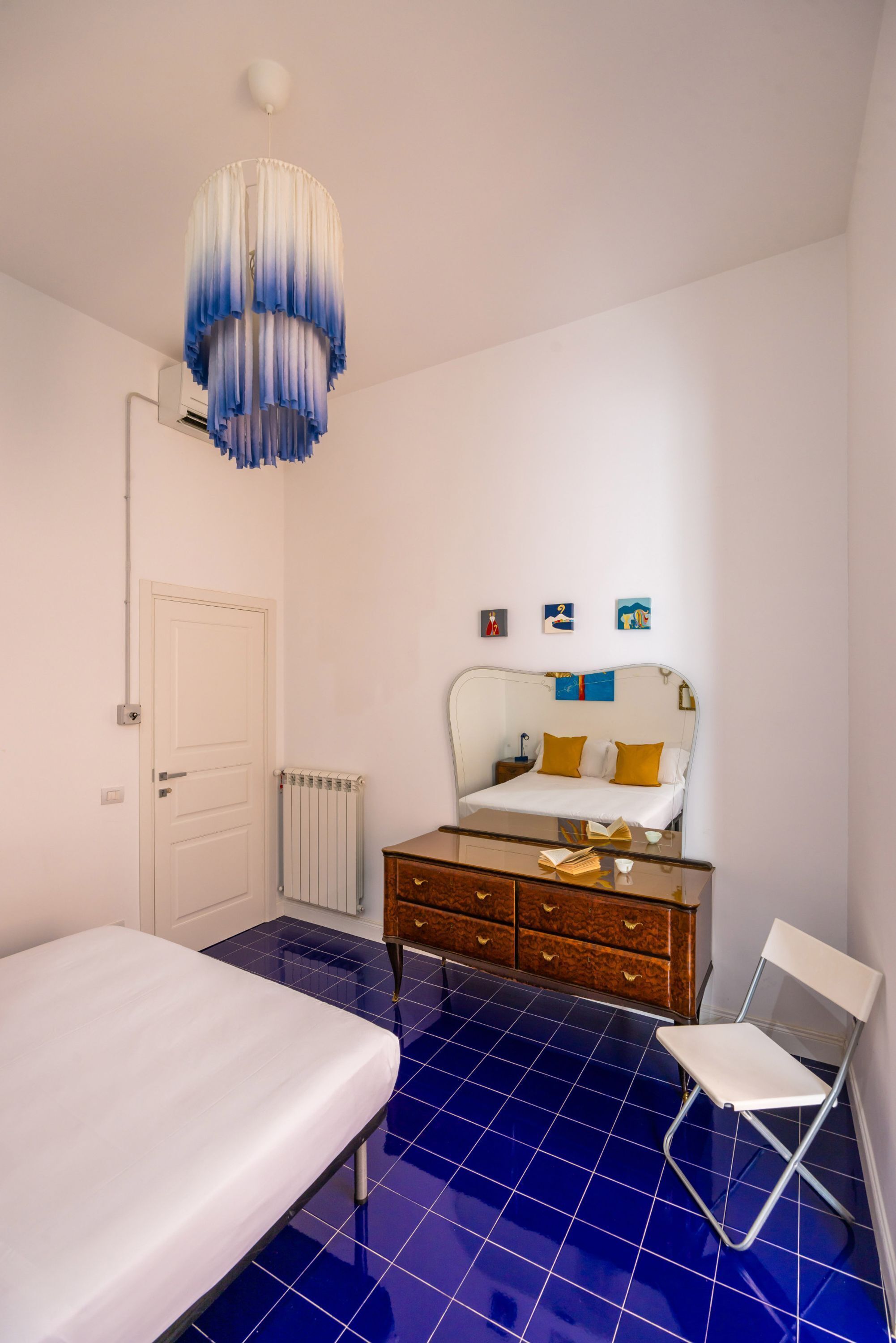 Ein Schlafzimmer mit Bett, Kommode, Stuhl, Heizkörper und Tür.