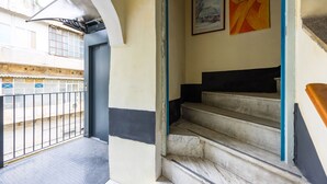 Un escalier revêtu de marbre, une rampe en métal et une porte donnant sur un espace extérieur agrémenté d’un portail en métal.