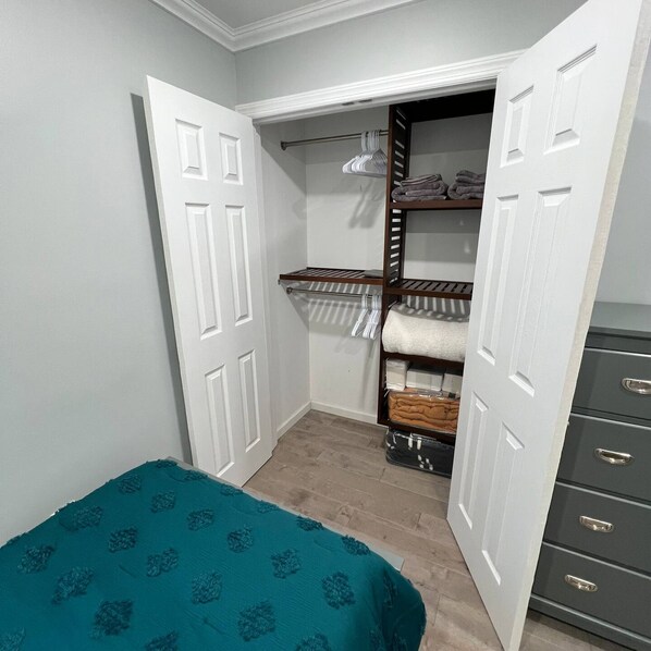 Une chambre à coucher comprenant un lit, une armoire et un placard intégré avec des étagères et une tringle pour suspendre les vêtements.