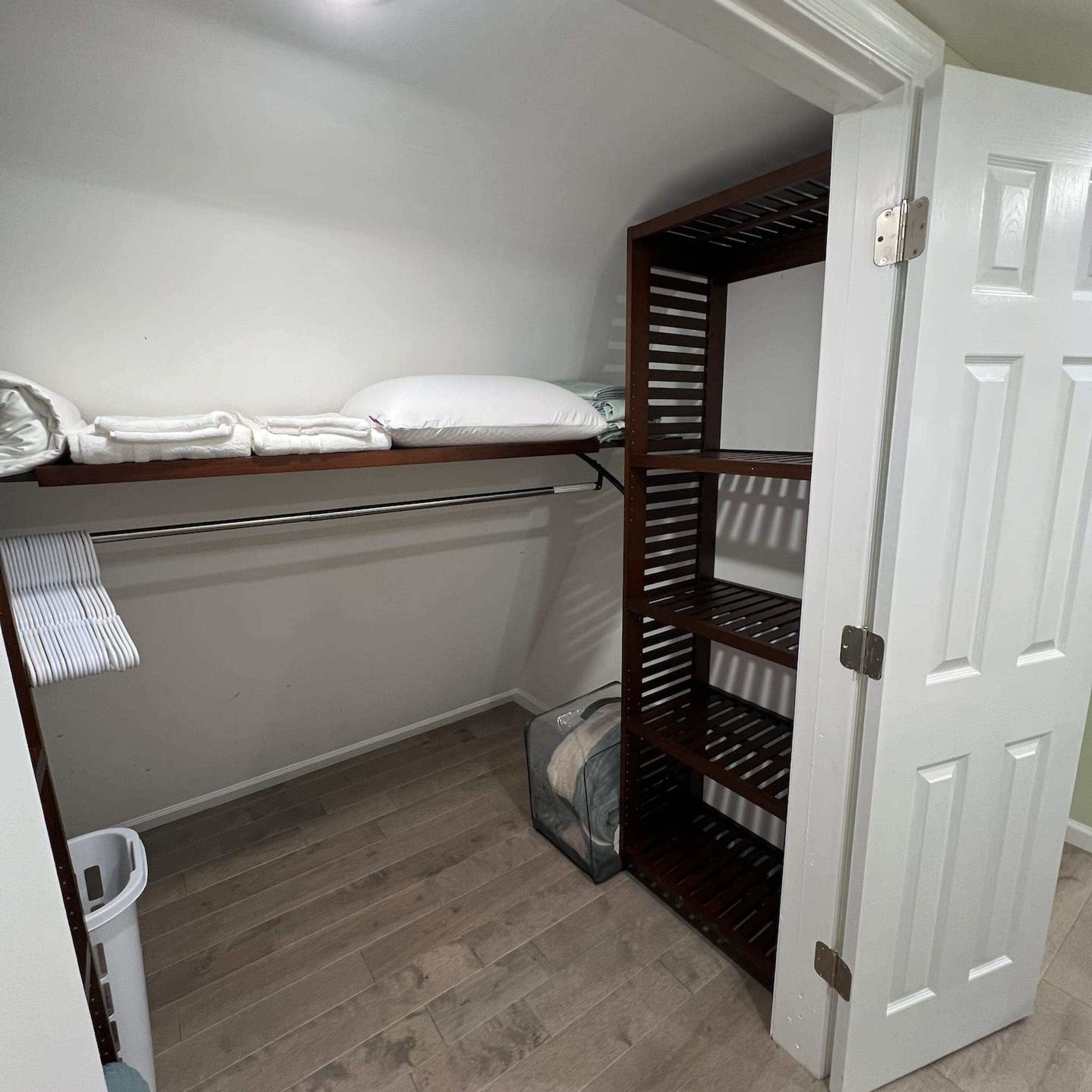 A small, enclosed storage area with a metal shelf holding folded towels and a white door.