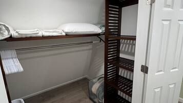 A small, enclosed storage area with a metal shelf holding folded towels and a white door.