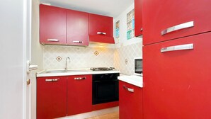 A kitchen with red cabinets, a black oven, and a white countertop. - 4bnb - Lante Apartment (Rome)