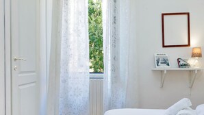 A bedroom with a bed, a window with curtains, a bedside lamp, and a framed picture on the wall. - 4bnb - Lante Apartment (Rome)