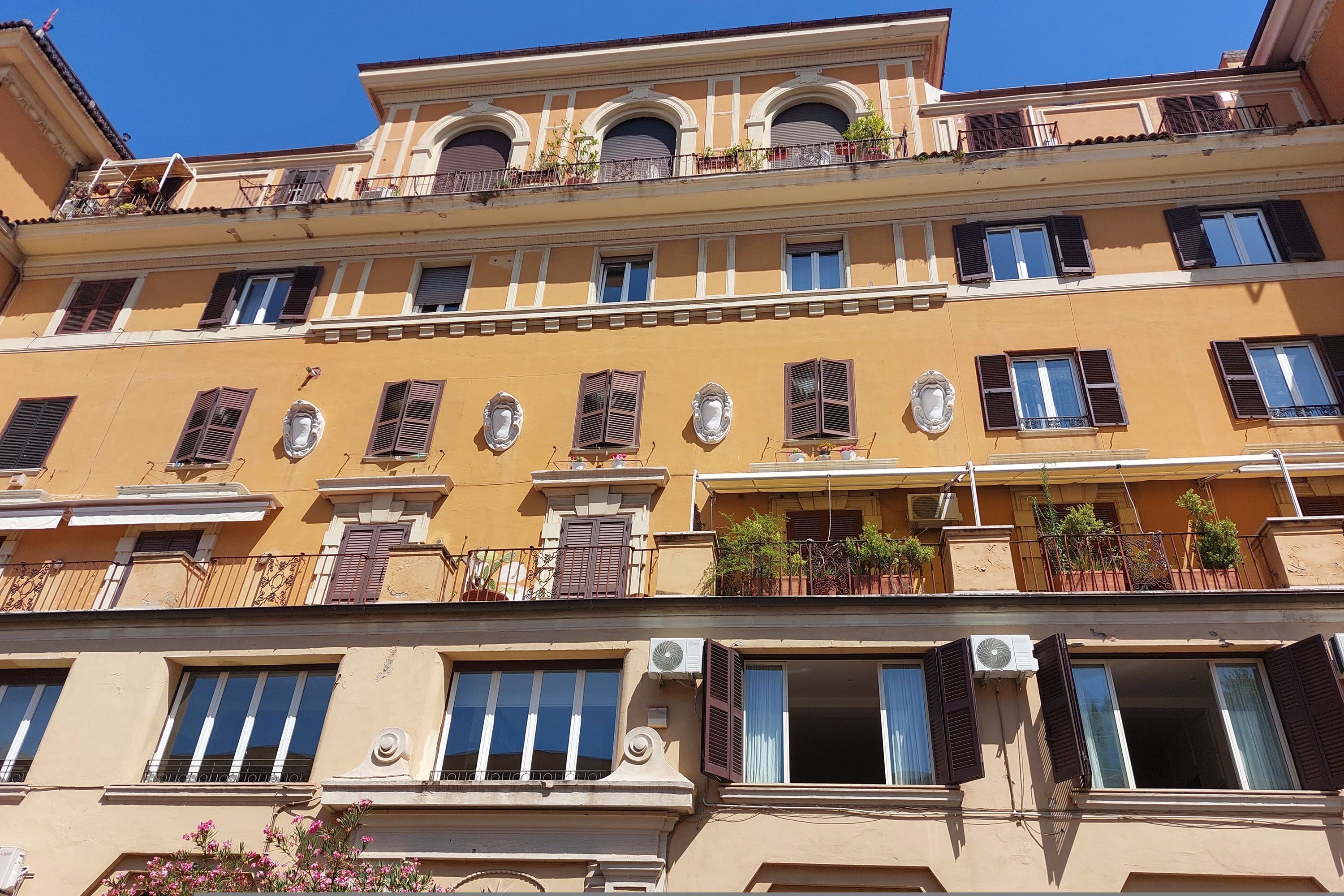 A multi-story building with balconies, windows with shutters, and air conditioning units.