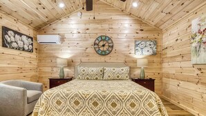 Een gezellig houten slaapkamer met een bed, twee nachtkastjes, een stoel en een wandklok.