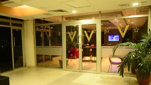 Un hall d’hôtel comprenant un comptoir d’accueil, un téléviseur et une grande plante en pot.