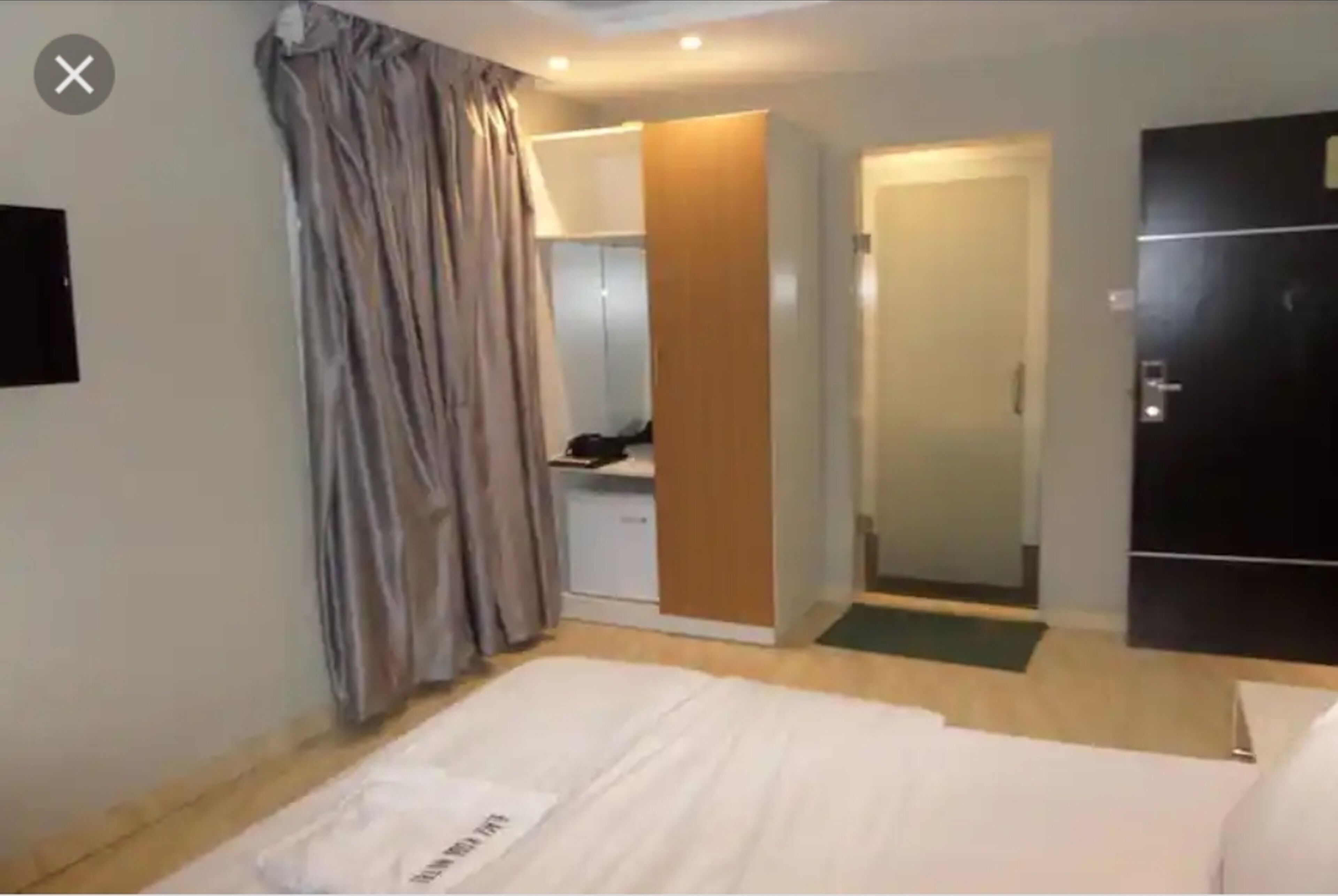 Una habitación de hotel con cama, armario, espejo y puerta.