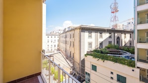 Un balcón con vistas a un edificio de arquitectura clásica y una grúa de construcción al fondo.