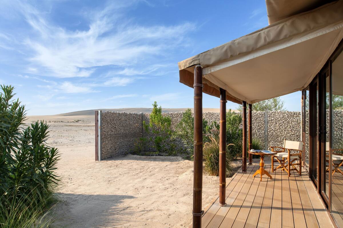 Un espacio al aire libre techado con una terraza de madera, una mesa y sillas.