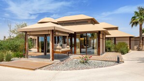 Ein modernes Haus mit Terrasse, Schaukel und Garten.