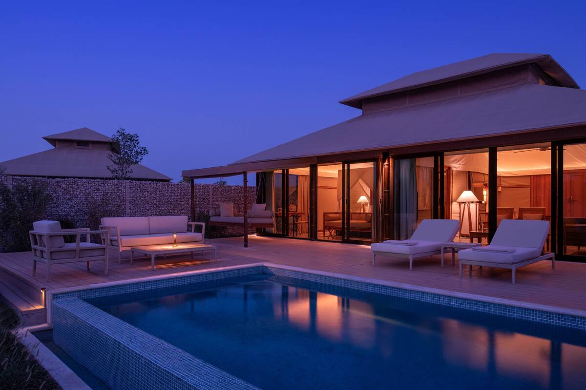 Un área moderna junto a la piscina con sillones de descanso y una piscina.