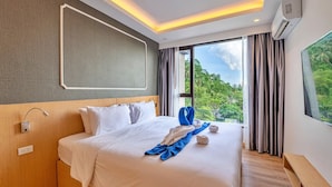 A hotel room with a large bed, a view of greenery, and a modern design. - Aristo 2 Phuket by RESAVA (Choeng Thale)