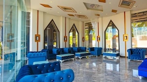 A spacious lobby with blue upholstered seating, large windows, and a modern ceiling design. - Aristo 2 Phuket by RESAVA (Choeng Thale)