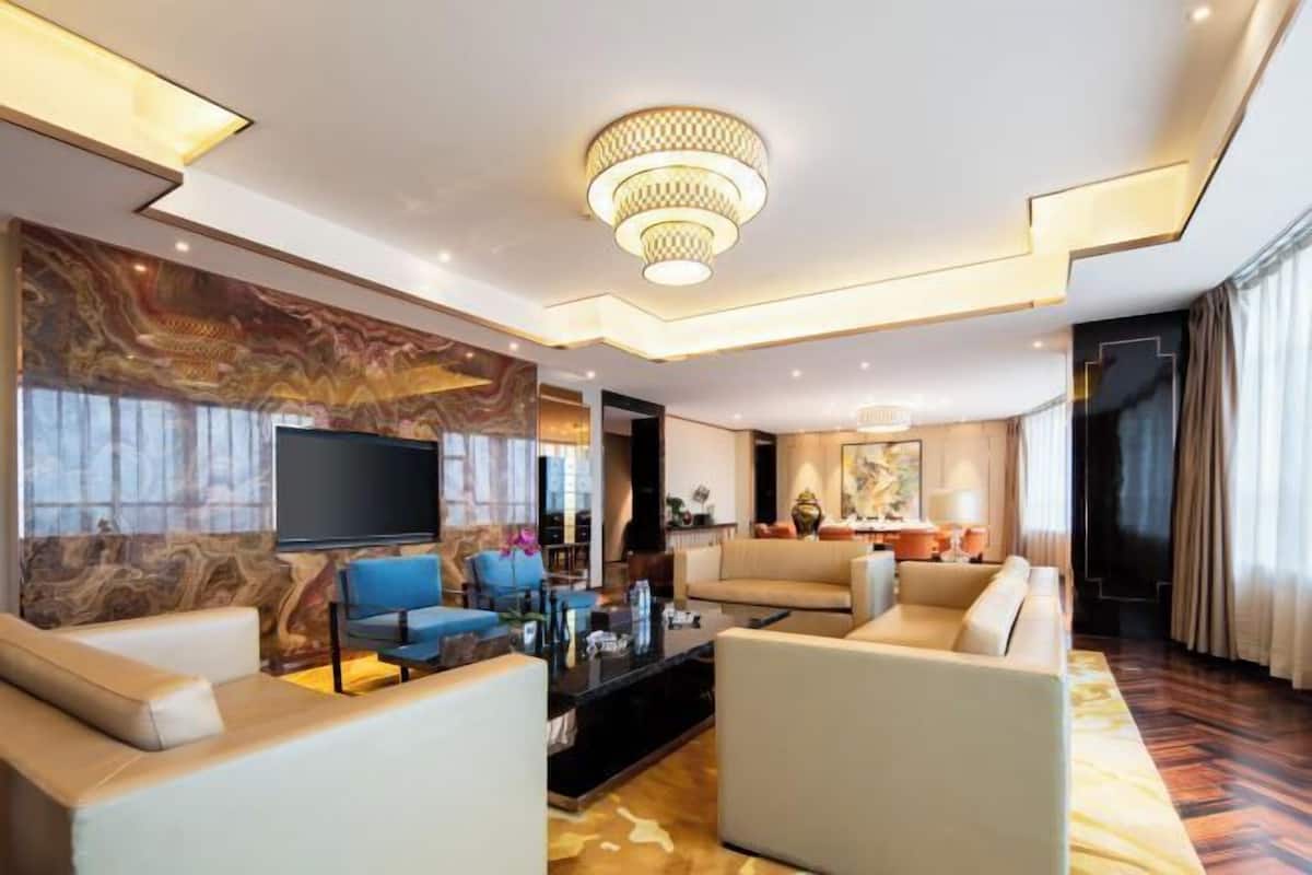 A modern living room with a flat-screen TV, sofas, a coffee table, and a decorative wall.