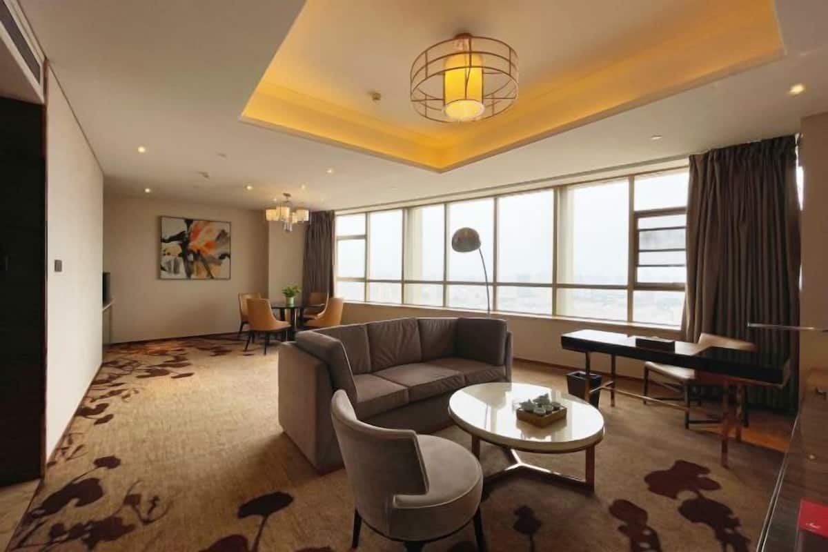 A modern living room with a sectional sofa, a round coffee table, and a large window with curtains.