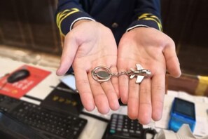 Une personne tenant un porte-clés avec une clé et un petit objet métallique.