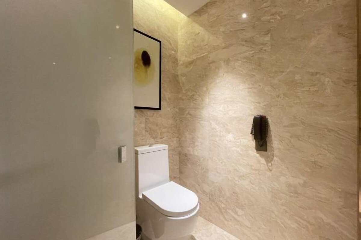 Une salle de bain moderne avec un mur en marbre, des toilettes blanches et un tableau encadré accroché au mur.