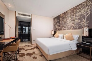 Une chambre d’hôtel avec un grand lit, un bureau avec une chaise, une télévision et un mur décoratif.