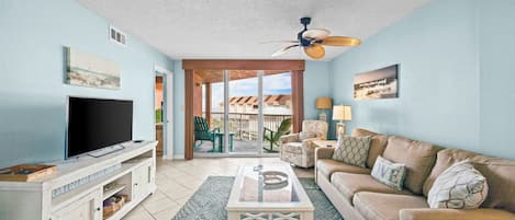 A living room with a TV, sofa, coffee table, and a balcony with a view.