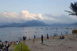 A beach with people, a tent, and a mountain in the background.