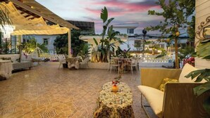 An outdoor patio area with a patterned floor, a round table with a vase, and a yellow sofa. - Jiandan'ai Hostel Shenzhen No. 1 (Shenzhen)