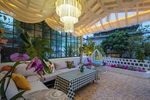 A spacious indoor area with a checkered bench, a sofa with cushions, and a hanging chandelier.
