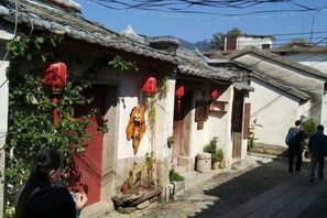 A traditional building with a tiled roof, a red lantern, and a hanging wooden sign.