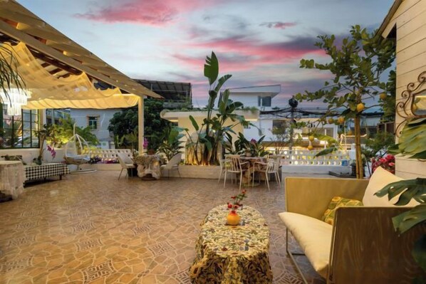 Une terrasse extérieure dotée d’un sol à motifs, d’un espace aménagé avec des sièges et d’une table décorative.