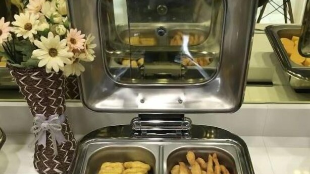 A buffet with two trays of food, one with breaded items and the other with fried items, and a decorative vase with flowers. - Jinjiang Inn Select Hotel (Tianjin Tanggu Subway Station Zhongxin North Road) (Tianjin)