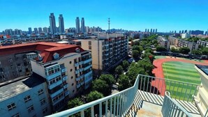 A high-rise building with multiple balconies, a red-roofed sports field, and a clear blue sky. - Jinjiang Inn Select Hotel (Tianjin Tanggu Subway Station Zhongxin North Road) (Tianjin)