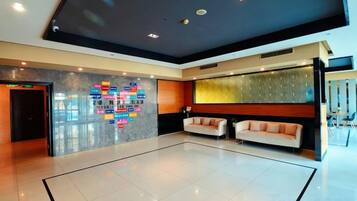A hotel lobby with a reception desk, a seating area with sofas, and a decorative wall with text.