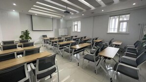 A classroom with rows of desks and chairs, a projector screen, windows, and a ceiling with recessed lighting. - Jinjiang Inn Select Hotel (Tianjin Tanggu Subway Station Zhongxin North Road) (Tianjin)