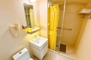 A bathroom with a toilet, sink, mirror, shower, and towel rack.