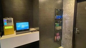 A modern bathroom with a dark textured wall, a small shelf with toiletries, and a laptop on a counter. - Jinjiang Inn Select Hotel (Tianjin Tanggu Subway Station Zhongxin North Road) (Tianjin)