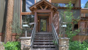 A wooden staircase leading to a front door with a stone base, flanked by two lantern-style lights. - Lenny's Lair | AC, Pool, Hot Tub, Golf & Ski (Durango)