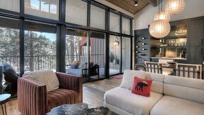 A modern interior with large windows, a cozy seating area, and a kitchen visible through the glass doors. - Lenny's Lair | AC, Pool, Hot Tub, Golf & Ski (Durango)
