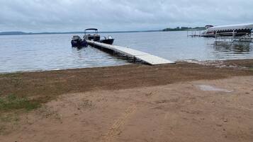 A sandy beach with a wooden pier extending into calm water.