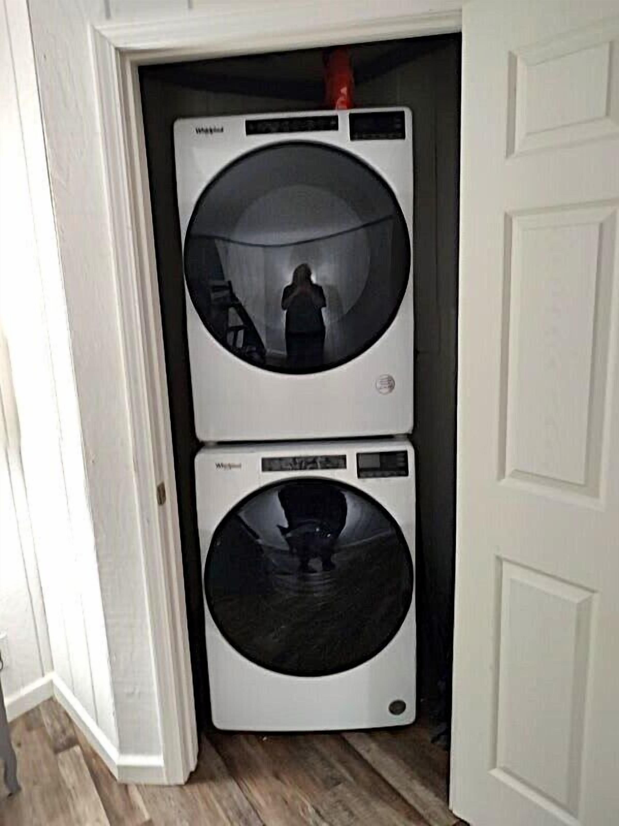 A compact, white laundry room with two stacked front-loading washing machines.