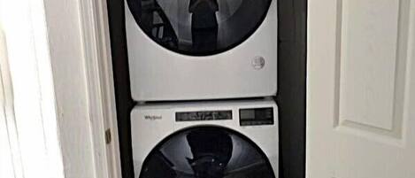 A compact, white laundry room with two stacked front-loading washing machines.