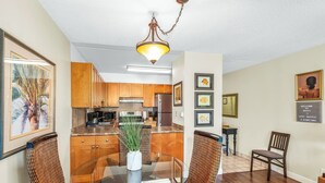 Una cocina moderna con armarios de madera, un refrigerador de acero inoxidable y una zona de comedor con sillas de mimbre y una mesa de vidrio.