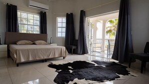 A bedroom with a bed, a cowhide rug, and a view of the outdoors. - Artiko Luxury Suites - Jan Thiel (Jan Thiel)